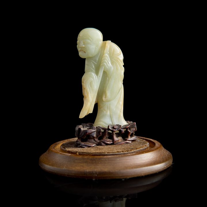 明代 白玉雕達摩(附原配硬木座及展示罩) A Chinese carved white jade Damo figure, Ming dynasty