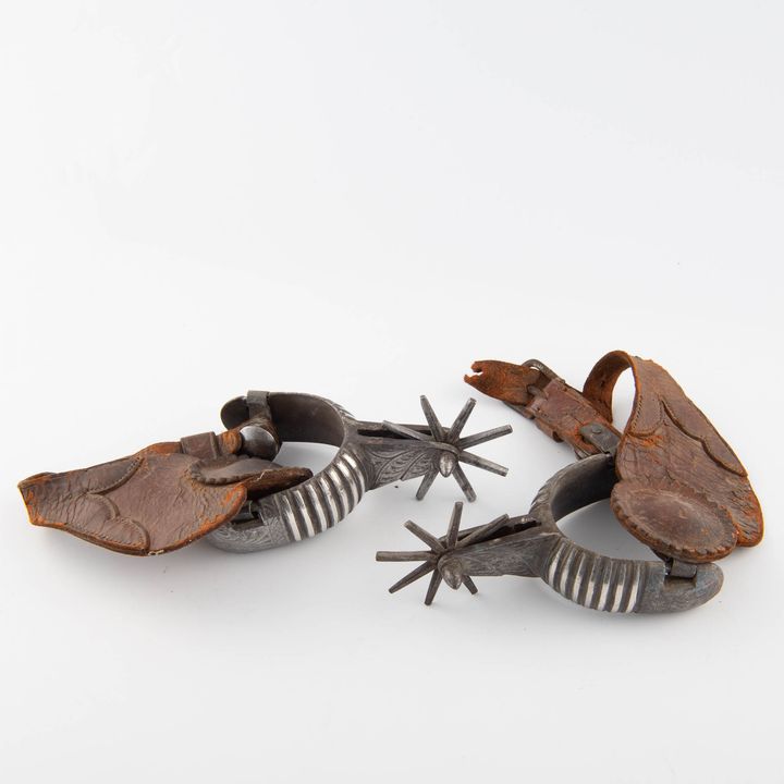 A pair of Mexican silver-inlaid iron spurs